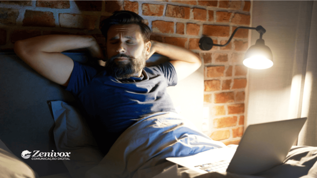 Homem relaxando na cama com um laptop ao lado, sob a luz de um abajur, simbolizando a busca por equilíbrio entre descanso e produtividade para melhorar o desempenho em vendas.
