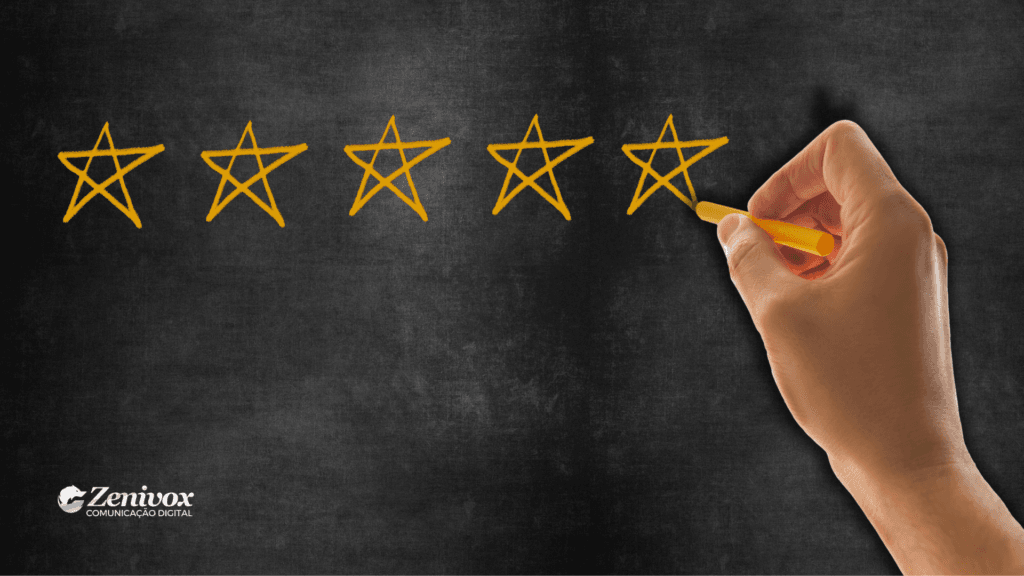 Imagem de uma mão segurando um giz amarelo, desenhando estrelas em um quadro-negro. A cena simboliza o processo de construção de avaliações positivas, representando esforço e atenção aos detalhes para alcançar excelência.