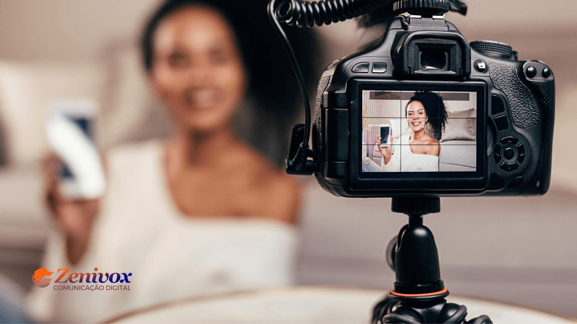 Mulher gravando um vídeo com uma câmera DSLR em um ambiente aconchegante. A tela da câmera foca no rosto da influenciadora, que sorri enquanto segura um smartphone, transmitindo profissionalismo e autenticidade. No canto inferior esquerdo, a marca Zenivox destaca a especialização em comunicação digital. A imagem representa o poder do VSL Marketing, enfatizando como vídeos bem produzidos podem converter leads em clientes de forma eficaz.