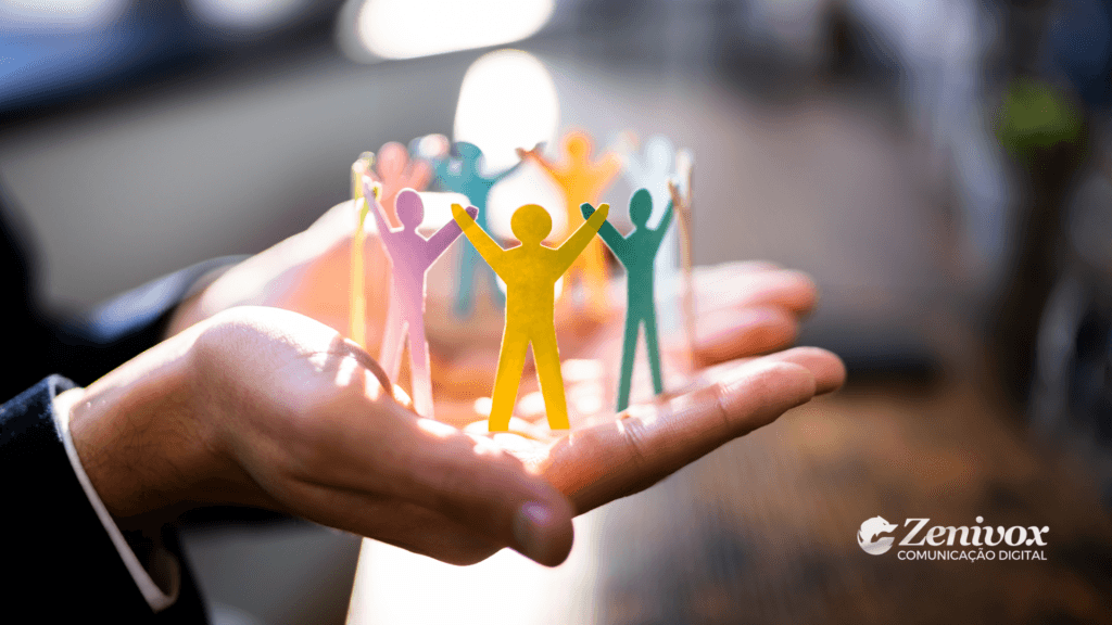 Imagem representando estilo de gestão e colaboração no ambiente de trabalho. Um grupo de figuras de papel coloridas, de mãos dadas, simboliza diferentes estilos de gestão e trabalho em equipe. A cena transmite harmonia, inclusão e liderança.