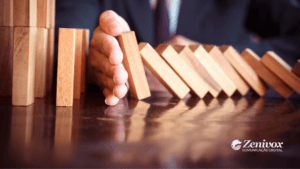 Uma mão detém o movimento de peças de dominó em queda, simbolizando o controle e a prevenção de problemas da gestão de processos. Com o logo da Zenivox Comunicação Digital no canto inferior direito.