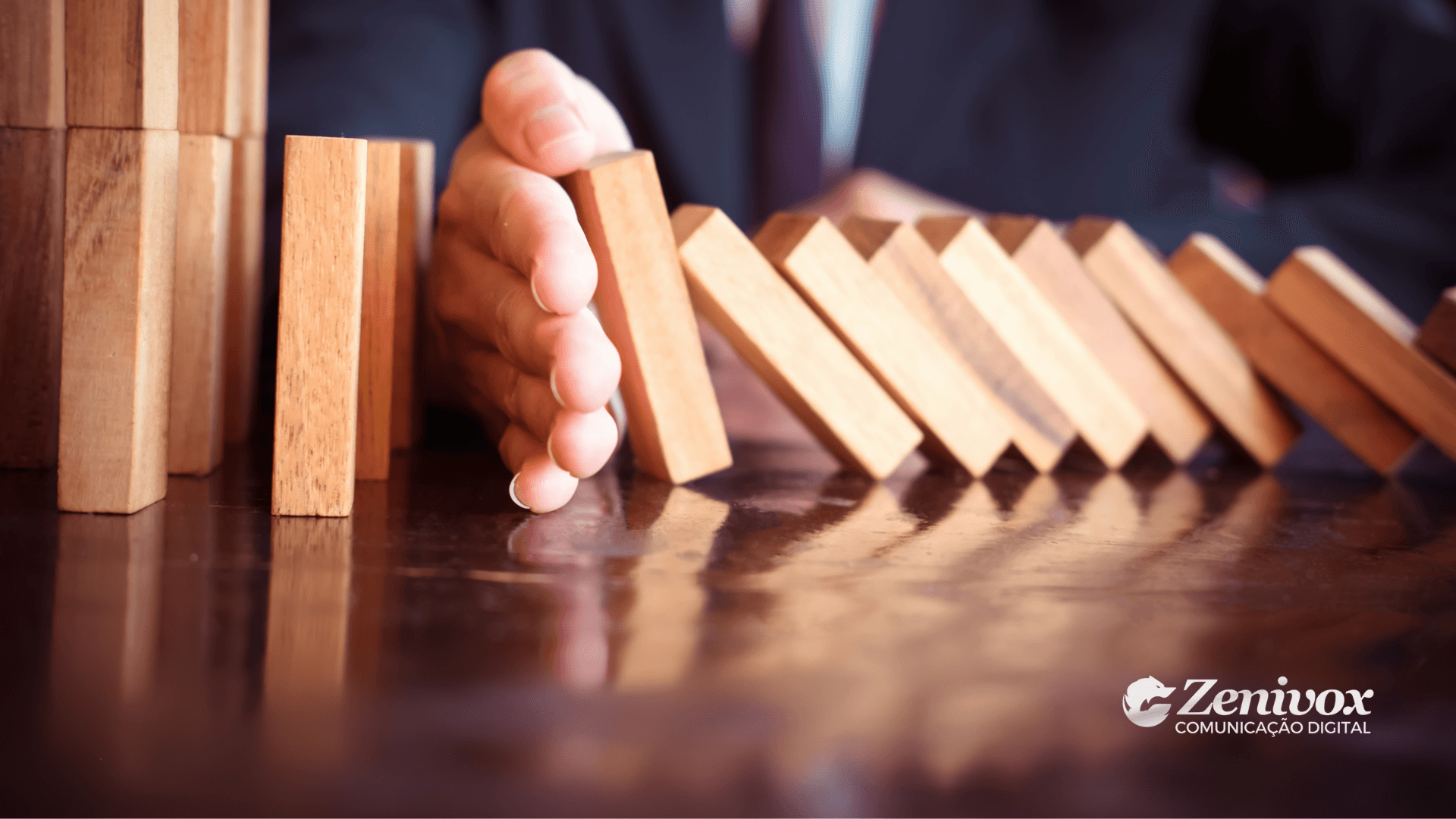 Uma mão detém o movimento de peças de dominó em queda, simbolizando o controle e a prevenção de problemas da gestão de processos. Com o logo da Zenivox Comunicação Digital no canto inferior direito.