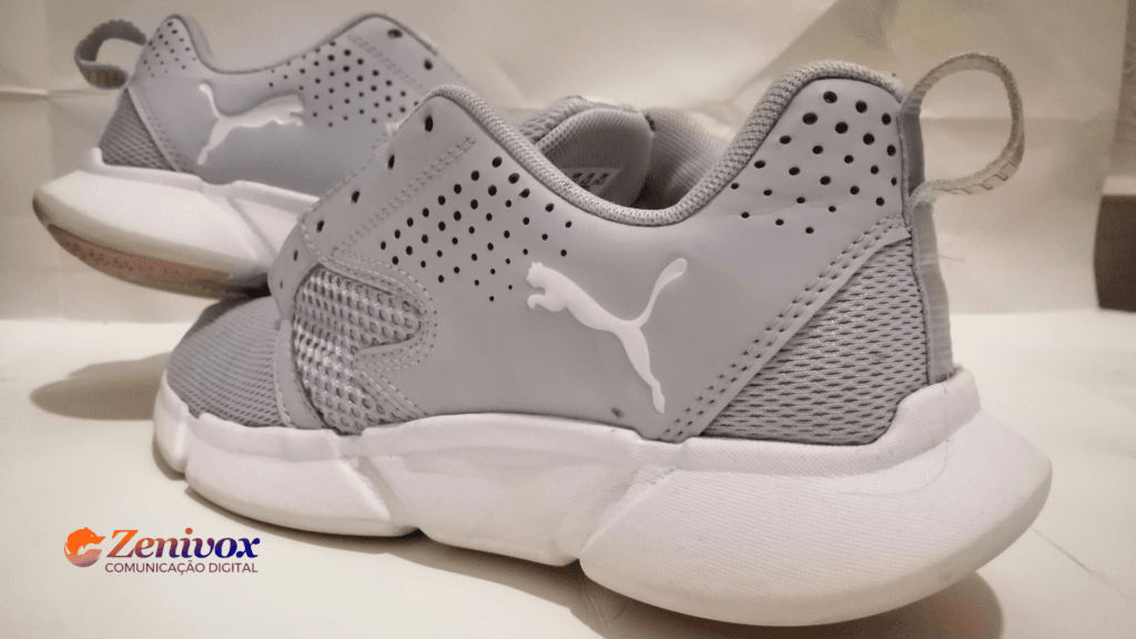 Par de tênis esportivos cinza da Puma, com design moderno, materiais respiráveis e acabamento de alta qualidade, refletindo a evolução contínua da estratégia de produto da marca em inovação e expansão global.