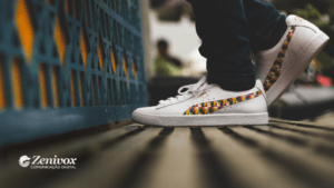 Tênis branco da marca Puma, com detalhes coloridos em forma de mosaico no design lateral, em um ambiente urbano, focado em estilo e atitude. Um elemento visual sonoro que reforça o conceito de velocidade e os 4 Ps do Marketing da Puma.