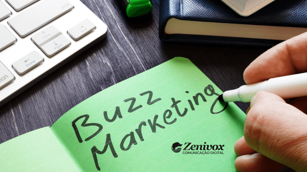 Imagem mostrando uma mão segurando uma caneta branca e escrevendo as palavras "Buzz Marketing" em um bloco de notas verde. No canto inferior direito, está o logotipo da Zenivox Comunicação Digital. Ao fundo, há um teclado, um marcador de texto verde e um caderno azul sobre uma mesa escura.