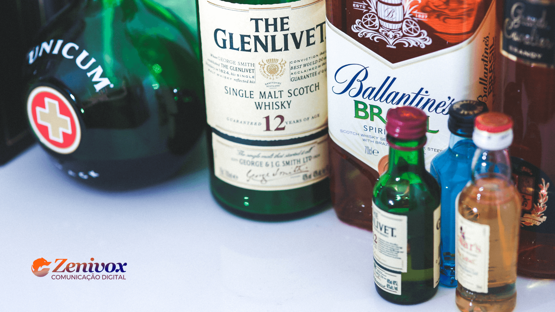 Portfólio de Produtos: Para Não Ficar na Ressaca do Mercado Misture como a Pernod Ricard: Um bom portfólio de produtos é a receita para o sucesso! Imagem com diversas garrafas de bebidas renomadas, incluindo The Glenlivet, Ballantine's Brasil e Unicum, destacando a variedade e qualidade que simbolizam um portfólio bem estruturado. A marca Zenivox aparece no canto inferior esquerdo, reforçando a ideia de comunicação digital e marketing estratégico para expandir seu leque de produtos e alcançar melhores resultados no mercado.