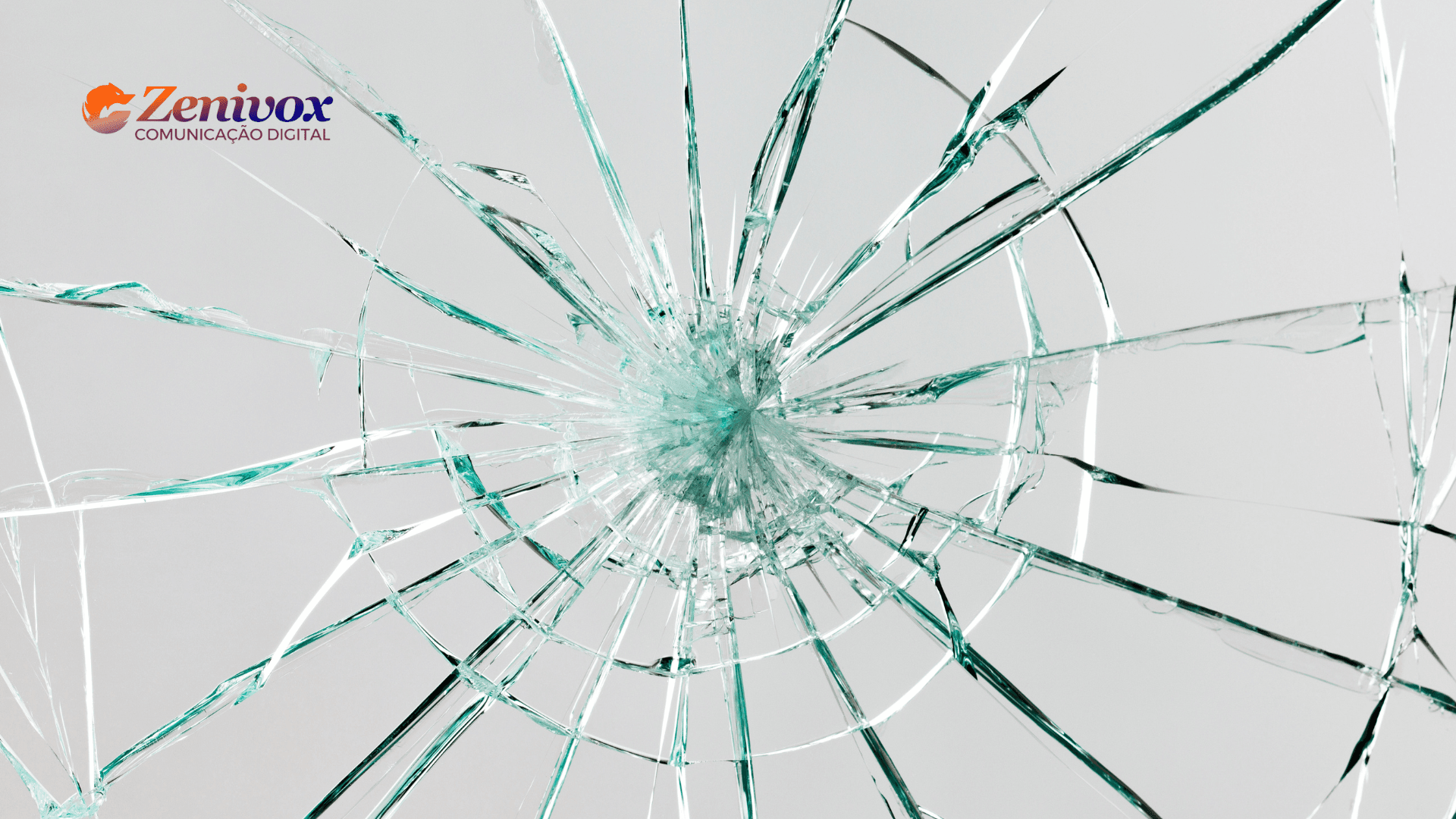 Imagem de um vidro quebrado com rachaduras partindo do centro em diversas direções. No canto superior esquerdo, há o logotipo da Zenivox Comunicação Digital, com as cores laranja e roxo destacando-se sobre o fundo claro. A imagem representa o conceito de "quebrar paradigmas" e inovação, simbolizando a abordagem disruptiva do Marketing Criativo.