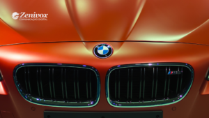 Close-up da grade frontal de uma BMW M5 em cor laranja metálica com o logotipo da Zenivox no canto superior esquerdo, simbolizando sofisticação, exclusividade e excelência na hora de gerar valor ao cliente.