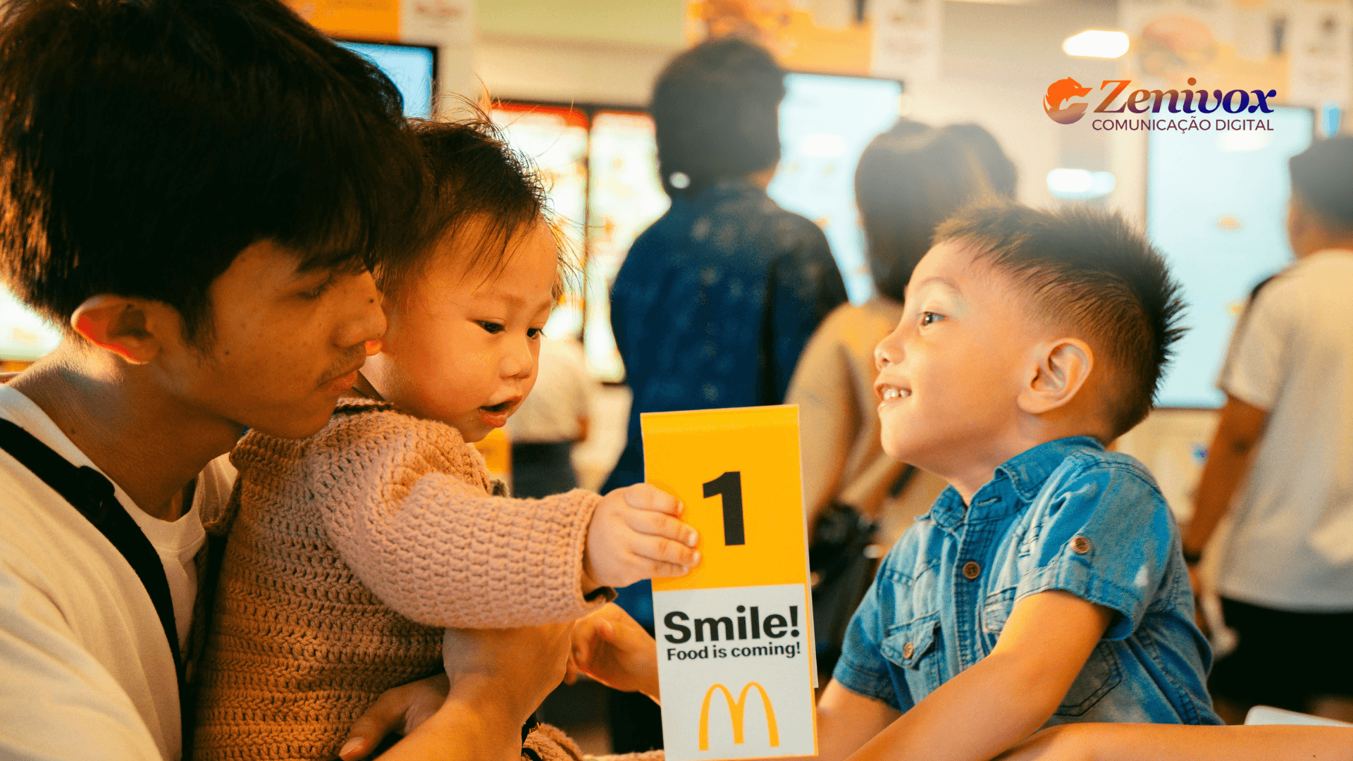Pai com dois filhos pequenos em um restaurante McDonald's, sorrindo enquanto interagem com o número de pedido, transmitindo um momento familiar, simbolizando o marketing emocional e a nostalgia.