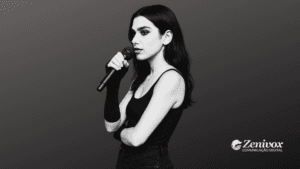 Dua Lipa com expressão séria e confiante segura um microfone enquanto olha para frente, representando postura firme e autenticidade, simbolizando o marketing pessoal. Ela veste roupas escuras e aparece sobre um fundo degradê minimalista, com o logotipo da Zenivox no canto inferior direito.