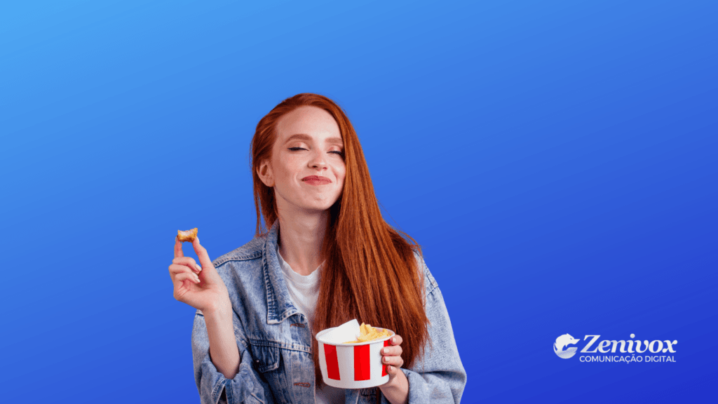 Mulher ruiva sorridente, com expressão de satisfação, segura um balde de batatas fritas no estilo KFC em uma mão e uma batata mordida na outra, simbolizando como a estratégia de marketing orgânico do KFC deu certo. Ela está em frente a um fundo azul vibrante, vestindo jaqueta jeans. No canto inferior direito aparece o logotipo da Zenivox Comunicação Digital.