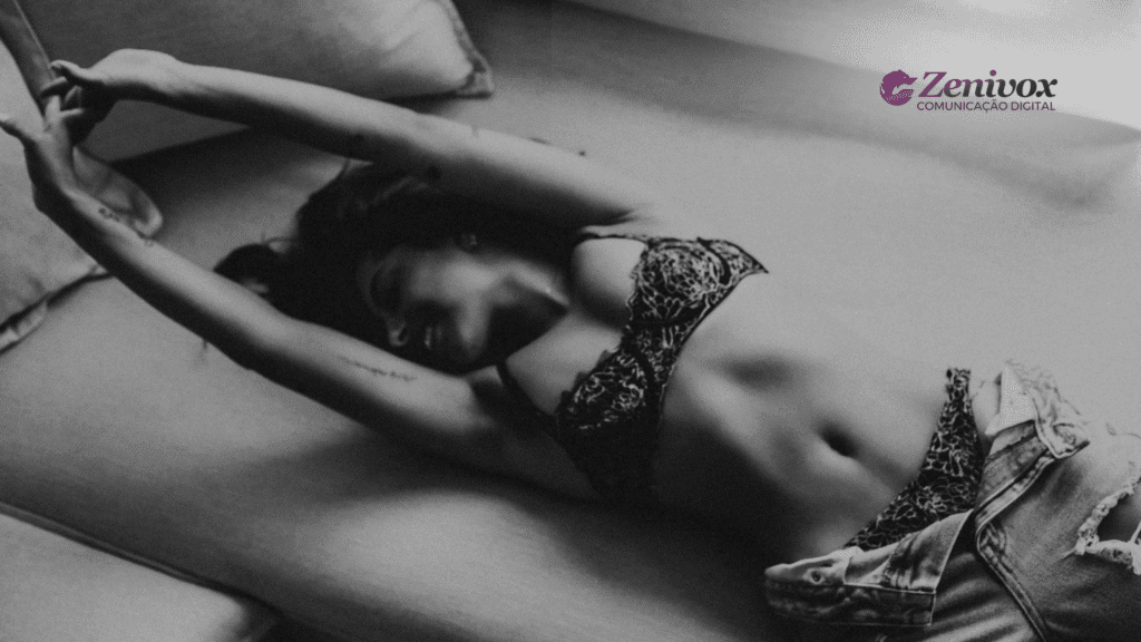Mulher deitada em um sofá, usando lingerie rendada e jeans, com expressão leve e descontraída. Imagem em preto e branco com tom sensual sutil, transmitindo a ideia de campanhas publicitárias sensuais com elegância sem vulgaridade. Branding da Zenivox visível no canto superior direito.