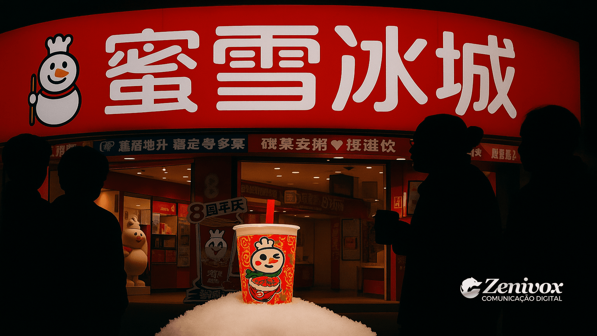 Fachada icônica da Mixue com destaque para o logotipo em vermelho e branco, reforçando a identidade visual da marca. Em primeiro plano, um copo promocional decorado com o mascote Snow King é exibido sobre um monte de neve artificial, enquanto silhuetas de consumidores observam a loja. A composição transmite a padronização visual das unidades da Mixue, que replicam o uso intenso de vermelho, branco e a figura do Snow King para criar reconhecimento imediato.