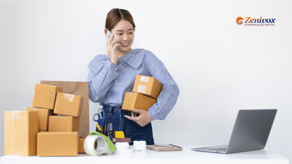 Mulher segurando caixas de encomenda e falando ao telefone enquanto observa o notebook, simbolizando o início das negociações digitais. Há vários pacotes sobre a mesa e o logo da Zenivox no canto superior direito.