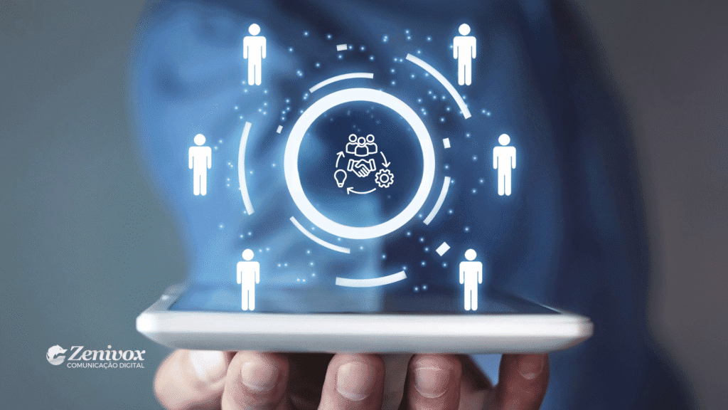 Pessoa segurando um smartphone com hologramas digitais de ícones representando pessoas e trabalho em equipe. No centro, um ícone de colaboração com figuras humanas, aperto de mão, lâmpada de ideia e engrenagem, simbolizando ferramentas para gestão participativa. No canto inferior esquerdo, o logo da Zenivox Comunicação Digital.