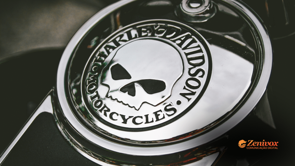 Close no emblema cromado da Harley-Davidson com caveira estilizada, gravado sobre a tampa metálica de uma motocicleta. A imagem transmite atitude, personalidade e o espírito ousado que compõe os pilares da identidade de marca forte.