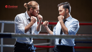 Dois homens vestindo roupas sociais, dentro de um ringue de boxe, posicionados em guarda de luta, simbolizando um confronto profissional, que vai ser parado pela gestão de conflitos. No canto superior esquerdo está o logotipo da Zenivox Comunicação Digital.