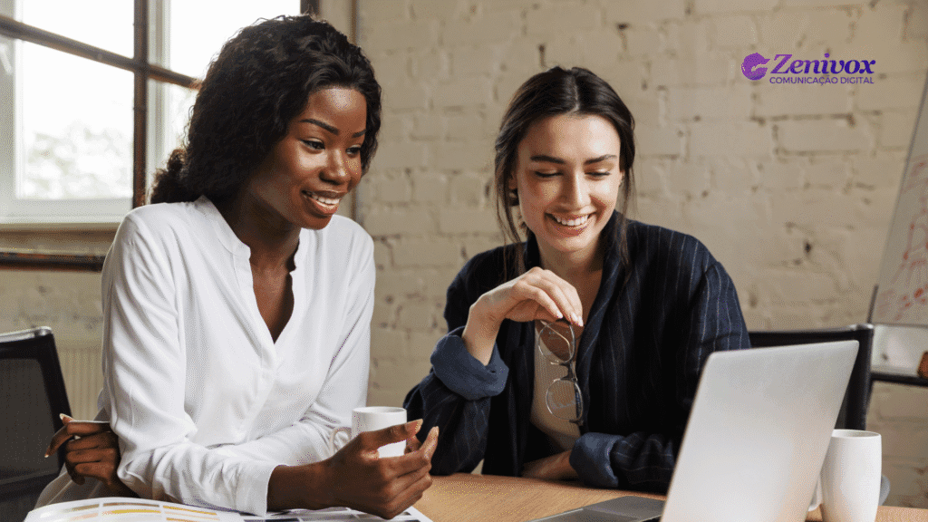 Duas mulheres empreendedoras sorridentes observam um notebook em ambiente de trabalho moderno. A imagem transmite parceria, confiança e planejamento. No canto superior direito, o logotipo da Zenivox Comunicação Digital.