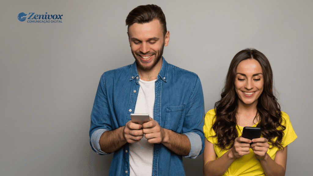 Homem e mulher sorridentes usando seus smartphones lado a lado, representando o comportamento de consumo dos millennials l, conectado e interativo típico dos millennials ao consumir conteúdo e tomar decisões de compra.