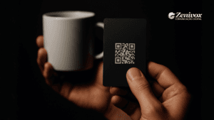 Mão segurando um cartão elegante com QR Code ao lado de uma xícara de café, representando mimos para clientes pensados para encantar, gerar valor e fortalecer relacionamento com a marca.